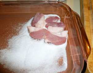 Dredged pork belly slices on salt and sugar mixture layer